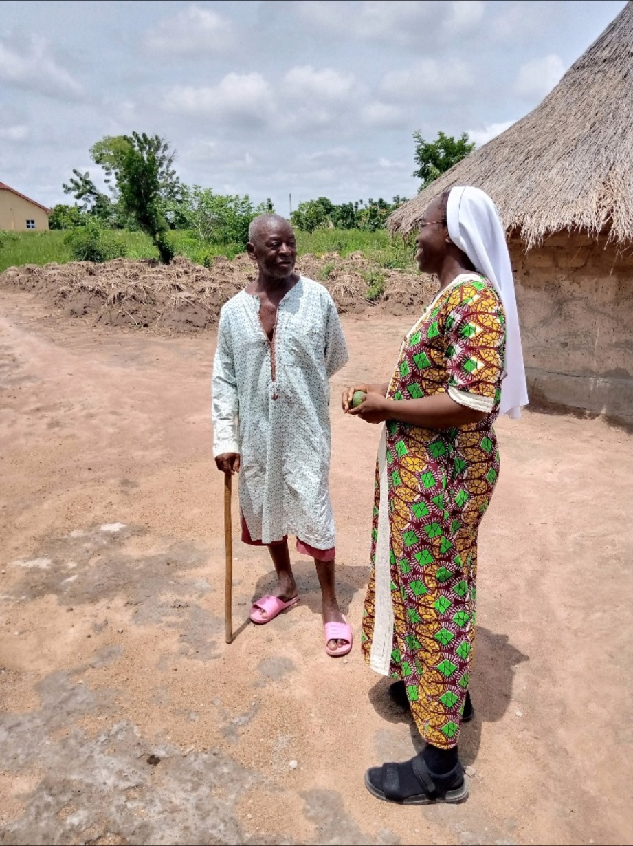 An ACMC missionary in conversation with an elderly man during village outreach
